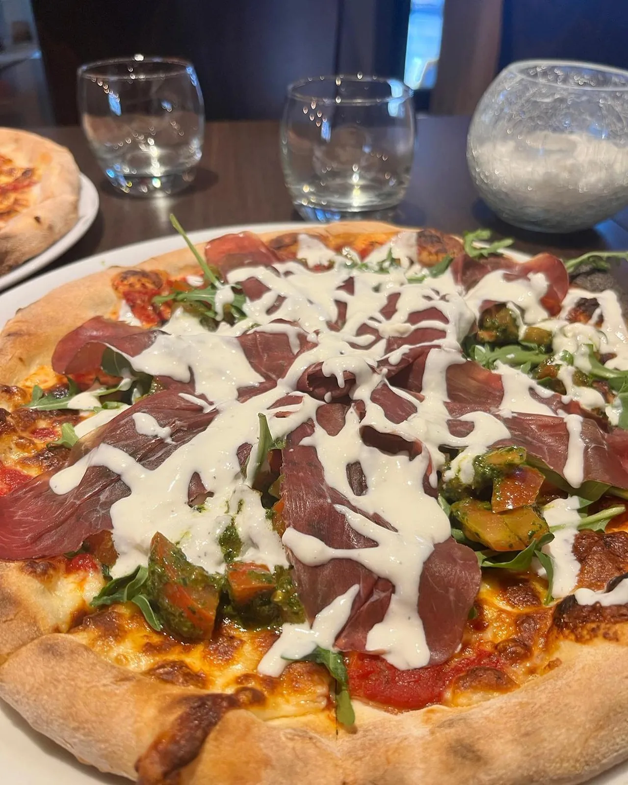 Pizza au jambon cru, roquette et crème de burrata en salle