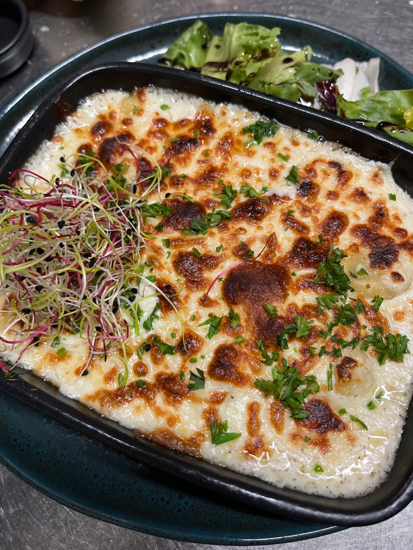 Gratin de pâtes au four gratiné au parmesan, salade et pousses fraîches